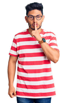 Handsome latin american young man wearing casual clothes and glasses asking to be quiet with finger on lips. silence and secret concept.
