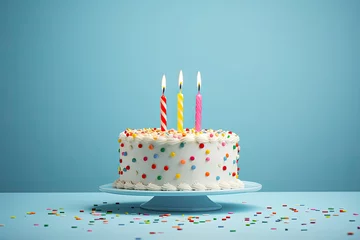 Poster Tarta de cumpleaños de nata con virutas de chocolate de colores con tres velas encendidas, sobre plato y fondo azul claro. concepto cumpleaños y aniversarios © Helena GARCIA