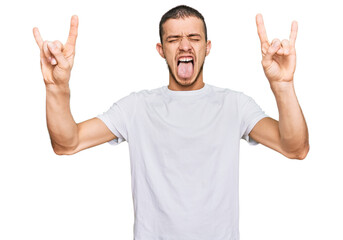 Hispanic young man wearing casual white t shirt shouting with crazy expression doing rock symbol with hands up. music star. heavy concept.