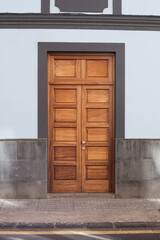 Wooden door yellow paint wall. Spanish european architecture background. Pavement and street. Urban background. Wooden door house entrance. Retro antique home facade.