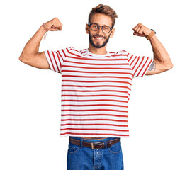 Fototapeta premium Handsome blond man with beard wearing casual clothes and glasses showing arms muscles smiling proud. fitness concept.