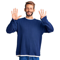 Handsome blond man with beard wearing casual sweater showing and pointing up with fingers number...