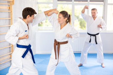 Obraz premium Guy and girl training wrestling fighting. Athletes repeat and practice basic techniques of kicks and punches. Coach prepares martial arts athletes for competitive program