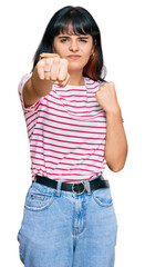 Young hispanic girl wearing casual clothes punching fist to fight, aggressive and angry attack,...