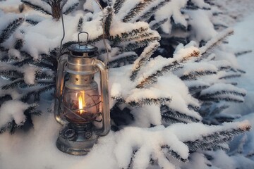a winter kerosene lantern shines in the branches of a Christmas tree.
