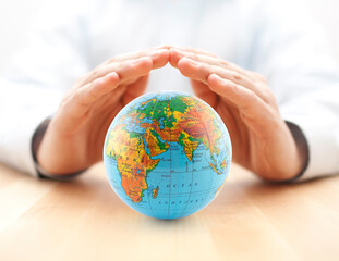 Planet Earth globe protected by hands.