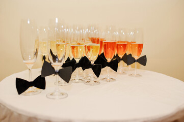 Champagne or white wine drink in glasses on a round table decorated with black bows. New Year....