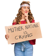 Young blonde girl wearing hippie style holding mother nature is crying protest cardboard banner...