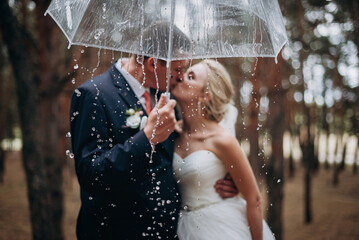 Romantic newlyweds under umbrella. Selective focus - obrazy, fototapety, plakaty