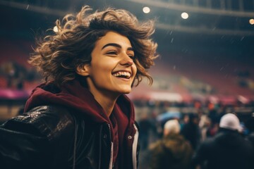 a soccer fan woman with short hair, her face radiating pure joy, excitement, and passion as she cheers enthusiastically in front of the stadium during a thrilling match