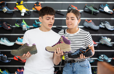 Fototapeta na wymiar Guy and girl choose climbing shoes together in a sports store