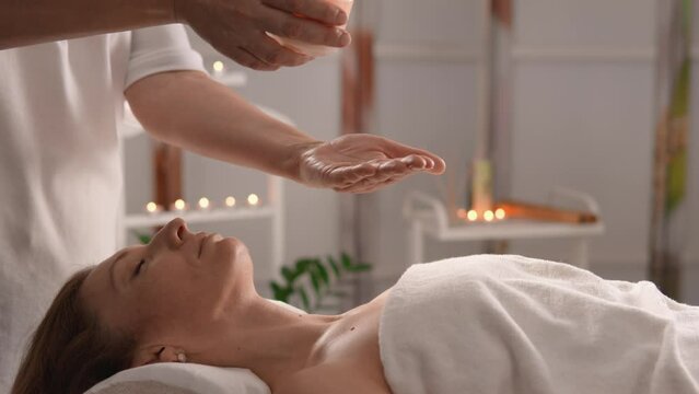 The massage therapist applies new trendy spa techniques, providing clients with maximum relaxation and pleasure. Coconut oil from a candle for applying and massaging skin. Woman relaxing in harmony