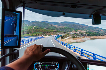 View from the driving position of a truck of a viaduct and a swamp below, vehicle equipped with camera rearview mirrors.
