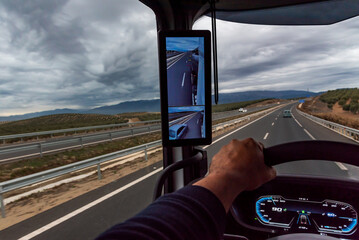 View from the driving position of a truck of a road with storm clouds above, vehicle equipped with...
