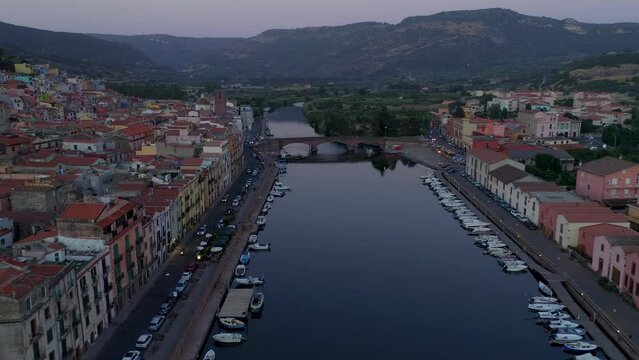 Aerial drone view of Bosa historic city colorful houses with Temo river and historic bridge at sunset in Sardinia, Italy