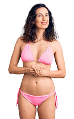Obraz premium Young beautiful hispanic woman wearing bikini with hands together and crossed fingers smiling relaxed and cheerful. success and optimistic