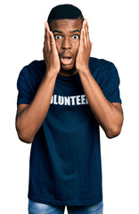 Fototapeta premium Young african american man wearing volunteer t shirt afraid and shocked, surprise and amazed expression with hands on face