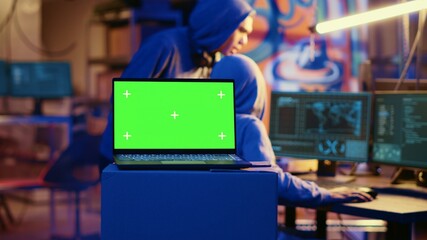 Green screen laptop in bunker with graffiti walls left behind by hackers to act as decoy. Mockup device running script pinging wrong location to cybercriminal law enforcement chasing them