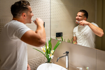 Man facing the mirror cleaning teeth at home