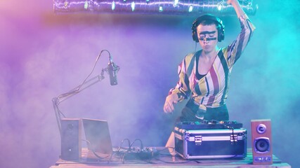 Cool DJ artist using vinyl records to mix music at turntables, doing remix mash of techno tunes...