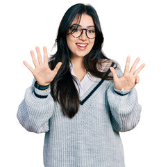 Beautiful hispanic woman wearing casual sweater and glasses showing and pointing up with fingers...