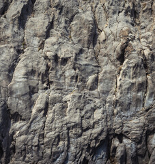 Weathered seaside rock face texture. Aged volcanic stone wall surface background pattern with cracks and scratches. Ischia Island, Italy.