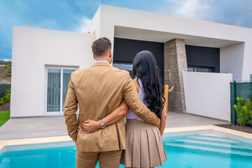 Couple facing their new luxury home from the pool