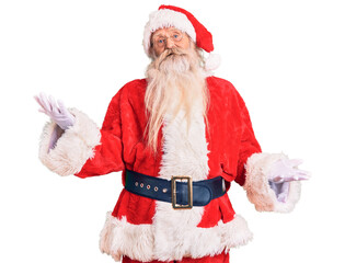 Old senior man with grey hair and long beard wearing traditional santa claus costume smiling cheerful with open arms as friendly welcome, positive and confident greetings