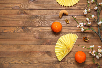 Composition with blooming sakura branch, Chinese symbols and tangerines on wooden background. New...