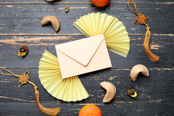 Composition with envelope, Chinese symbols, fortune cookies and tangerines on dark wooden...