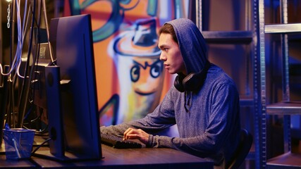 Happy asian hacker in graffiti painted hideout having burst of joy after managing to steal valuable data, using phishing technique that tricks users into revealing sensitive information