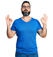 Fototapeta premium Hispanic man with beard wearing casual t shirt and glasses relax and smiling with eyes closed doing meditation gesture with fingers. yoga concept.
