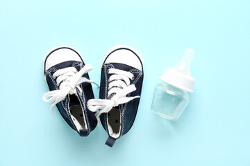 Shoes and baby bottle on blue background