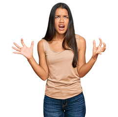 Beautiful hispanic woman wearing casual clothes crazy and mad shouting and yelling with aggressive expression and arms raised. frustration concept.