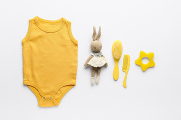 Cotton baby clothes, knitted toy and combs on white background