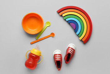 Educational toy blocks, baby feeding set and shoes on grey background