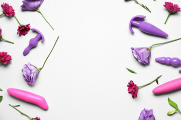 Different sex toys and beautiful flowers on light background
