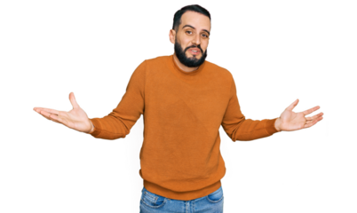 Young man with beard wearing casual winter sweater clueless and confused expression with arms and hands raised. doubt concept.