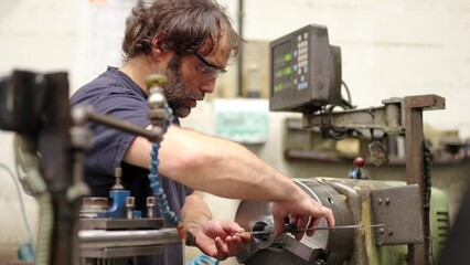 Video of a worker polishing a piece of metal in a industrial machine in a cnc factory