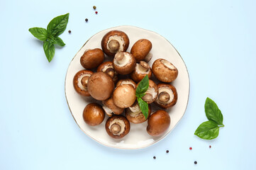 Plate with raw champignon mushrooms and spices on white background