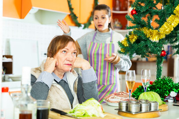 Portrait of upset senior woman having conflict with daughter during cooking xmas dinner