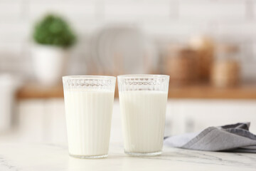 Glasses of fresh milk on white table