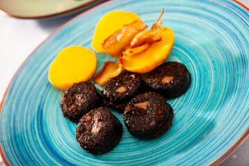 Fried morcilla (blood sausage with rice) served with side dish of baked potatoes