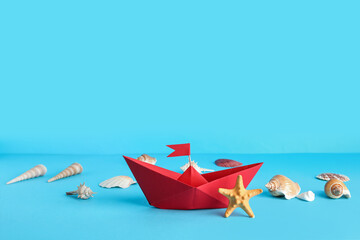 Red origami boat with seashells and starfish on blue background