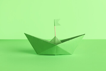 Origami boat with flag on green background