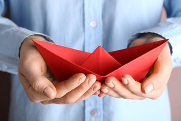 Woman holding red origami boat, closeup