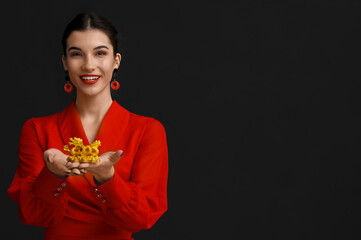 Beautiful young happy woman with golden dragon figurine on black background. Chinese New Year...