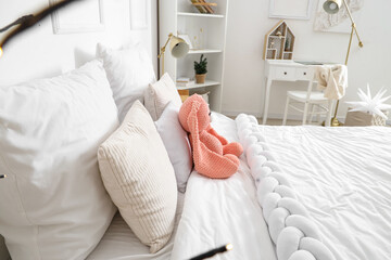 Cozy bed with plush bunny toy in children's bedroom - obrazy, fototapety, plakaty