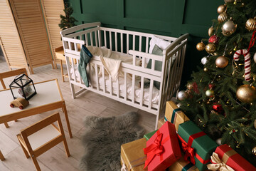 Interior of cozy nursery room with crib, Christmas tree and gifts