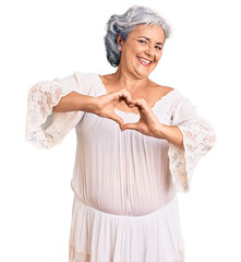 Senior woman with gray hair wearing bohemian style smiling in love doing heart symbol shape with hands. romantic concept.